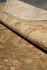 Load image into Gallery viewer, A close-up of a folded area rug showing its plush pile and detailed traditional floral pattern in warm beige, tan, and muted red tones.