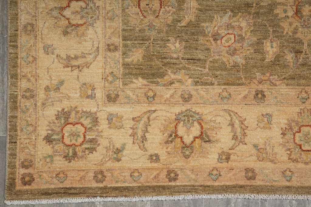 A close-up of an ornate area rug showing its detailed border and floral motifs in beige, brown, and muted red tones.