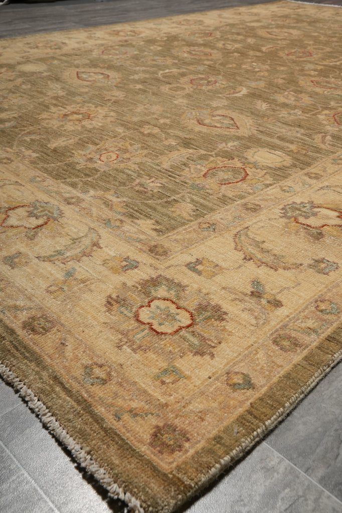 A traditional oriental-style area rug with a beige and brown base, featuring faded floral medallions and a patterned border, shown laid out on a gray tiled floor.