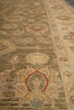 Load image into Gallery viewer, A close-up view of an area rug with a distressed traditional pattern in muted beige, olive green, and brown tones, featuring red and light blue accents.