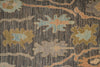 Load image into Gallery viewer, A close-up of a textured area rug featuring a vertical striped base in charcoal gray and brown, decorated with abstract floral motifs in muted blue, tan, and peach.