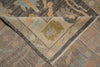 Load image into Gallery viewer, Close-up of a woven area rug corner showing a geometric and floral pattern in muted gray, beige, light blue, and tan tones.