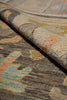 Load image into Gallery viewer, Close-up of a patterned area rug with a rolled corner showing the pile and texture. The design features abstract brushstroke patterns in beige, gray, brown, muted blue, and soft peach tones.