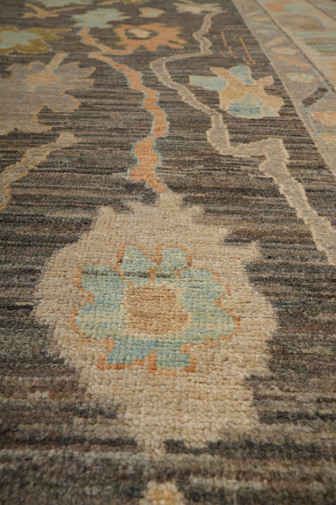 A close-up of a textured area rug featuring a traditional floral pattern in muted tones of beige, gray, light blue, and soft orange.