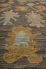 Load image into Gallery viewer, Close-up of a textured area rug featuring a traditional floral or medallion pattern in muted tones of blue, beige, and brown on a dark charcoal background.