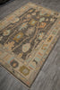 Load image into Gallery viewer, A rectangular area rug with a traditional floral and geometric pattern, shown laid out on a gray wood-look floor. The rug features a dark brown central field, a beige border, and accents of light blue, olive green, and tan.