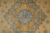 Load image into Gallery viewer, A close-up of a vintage-style geometric rug featuring a central star motif in muted blue-gray and ochre-brown tones on a tan background.