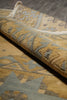 Load image into Gallery viewer, A close-up of a folded area rug showing its textured pile and traditional geometric pattern in muted beige, gray, and brown tones.