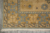Load image into Gallery viewer, A close-up of a patterned area rug corner showing a beige and gray geometric design with fringed edges on a gray floor.