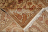 Load image into Gallery viewer, A close-up of a folded area rug with a traditional floral pattern in beige, brown, and muted red tones, featuring white fringe on one edge.