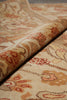 Load image into Gallery viewer, A close-up of a patterned area rug with a rolled section showing its texture and design. The rug features a traditional floral motif in beige, brown, and muted red tones.