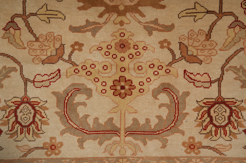 Close-up of a traditional patterned rug with a central floral medallion and scrolling vine motifs in beige, rust red, and brown tones.