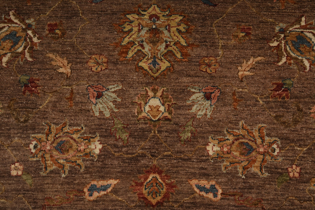 A close-up of a traditional patterned area rug with a brown base and ornate floral motifs in beige, rust red, blue, and muted green.