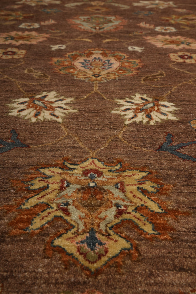 A close-up view of a traditional area rug with a brown base and ornate floral medallions in cream, rust orange, and blue.