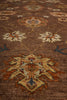 Load image into Gallery viewer, A close-up view of a traditional area rug with a brown base and ornate floral medallions in cream, rust orange, and blue.