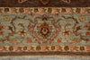 Load image into Gallery viewer, A close-up of an ornate patterned rug showing a central floral medallion and scrolling vine motifs in muted tones of sage green, rust red, beige, and brown, with a fringed edge at the bottom.