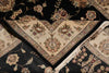 Load image into Gallery viewer, A close-up of a traditional oriental rug with a black field and a cream-colored V-shaped corner section featuring intricate floral and vine patterns in beige, green, and red.