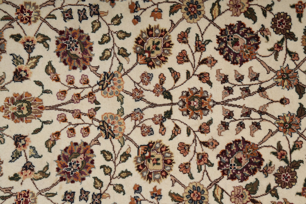Close-up of a traditional floral patterned rug with cream background and brown, beige, and muted blue botanical motifs.