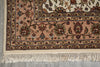 Load image into Gallery viewer, A close-up of a traditional patterned rug corner showing cream fringe, a dusty pink field, and ornate floral motifs in beige, brown, and muted red on a gray floor.