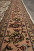 Load image into Gallery viewer, A close-up view of a traditional oriental runner rug with a floral pattern on a warm beige background, laid out on a gray tiled floor.