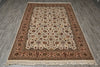 Load image into Gallery viewer, An oriental-style area rug with an intricate floral pattern, laid flat on a gray wood-look floor. The rug features a cream center field, a dusty rose border, and dark brown detailing, complete with a fringed edge.