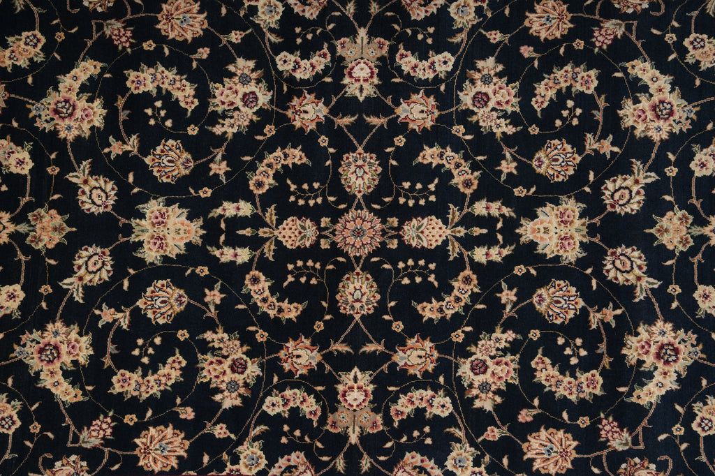 A close-up of an ornate traditional patterned rug with a dark navy or black background and intricate floral motifs in beige, cream, and muted red.