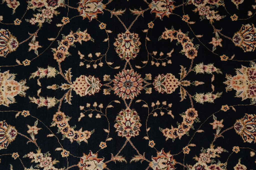 A close-up of an ornate floral patterned fabric or rug with a black background and cream, beige, and muted pink motifs.
