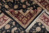 Load image into Gallery viewer, A folded traditional oriental rug with a dark navy blue field, deep red borders, and cream floral motifs, shown with fringe visible on one corner.