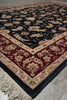 Load image into Gallery viewer, A traditional oriental area rug with a dark navy blue field, a deep red border, and cream floral motifs, shown on a light gray tiled floor.