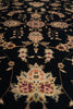 Load image into Gallery viewer, A close-up of a dark black or very deep navy area rug with an ornate traditional floral and vine pattern in beige, muted pink, and olive green.