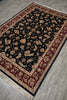 Load image into Gallery viewer, A rectangular area rug with a black central field, ornate floral motifs, and a burgundy and beige border, shown laid out on a gray wood floor.