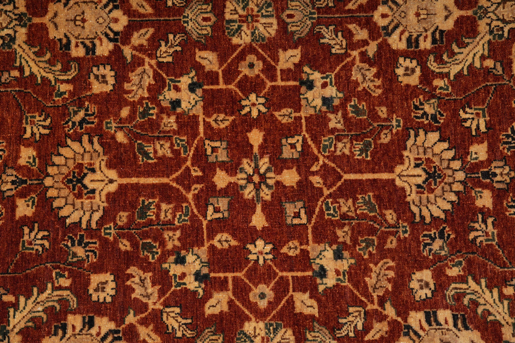 A close-up of an ornate traditional rug with a deep red-brown field, beige floral motifs, and dark green accents.