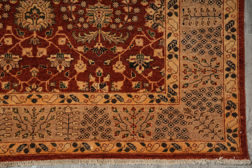A close-up of an oriental-style rug corner showing a warm rust red field with beige, black, and muted green floral motifs and a patterned border.