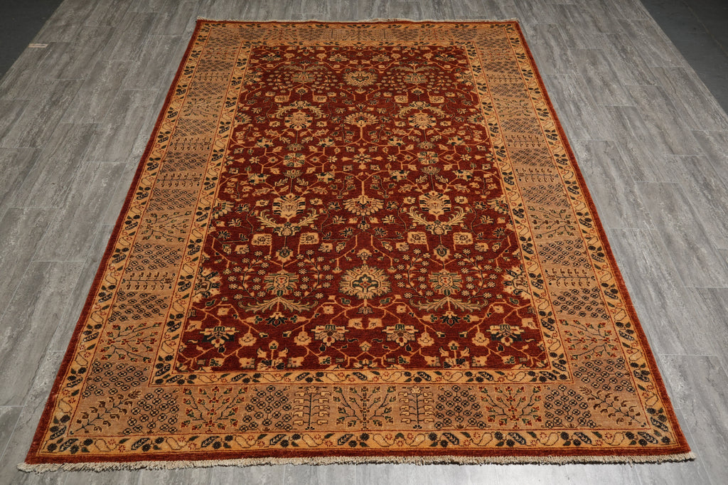 A traditional oriental area rug with a deep red central field and ornate beige, gold, and black floral motifs, laid out on a gray wood-look floor.
