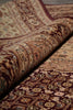 Load image into Gallery viewer, A close-up of a traditional oriental rug with a rolled section showing its detailed pattern and pile texture. The rug features a complex floral and geometric design in deep burgundy, beige, and brown tones.