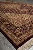 Load image into Gallery viewer, A traditional oriental-style area rug with an intricate floral and geometric pattern, shown laid out on a gray stone floor. The rug features a deep burgundy border, a beige center field, and cream fringe on the corner.