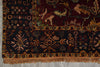 Load image into Gallery viewer, A close-up of an ornate patterned rug corner showing dark navy and burgundy fields with beige, gold, and muted green motifs, plus a fringed edge on a gray floor.