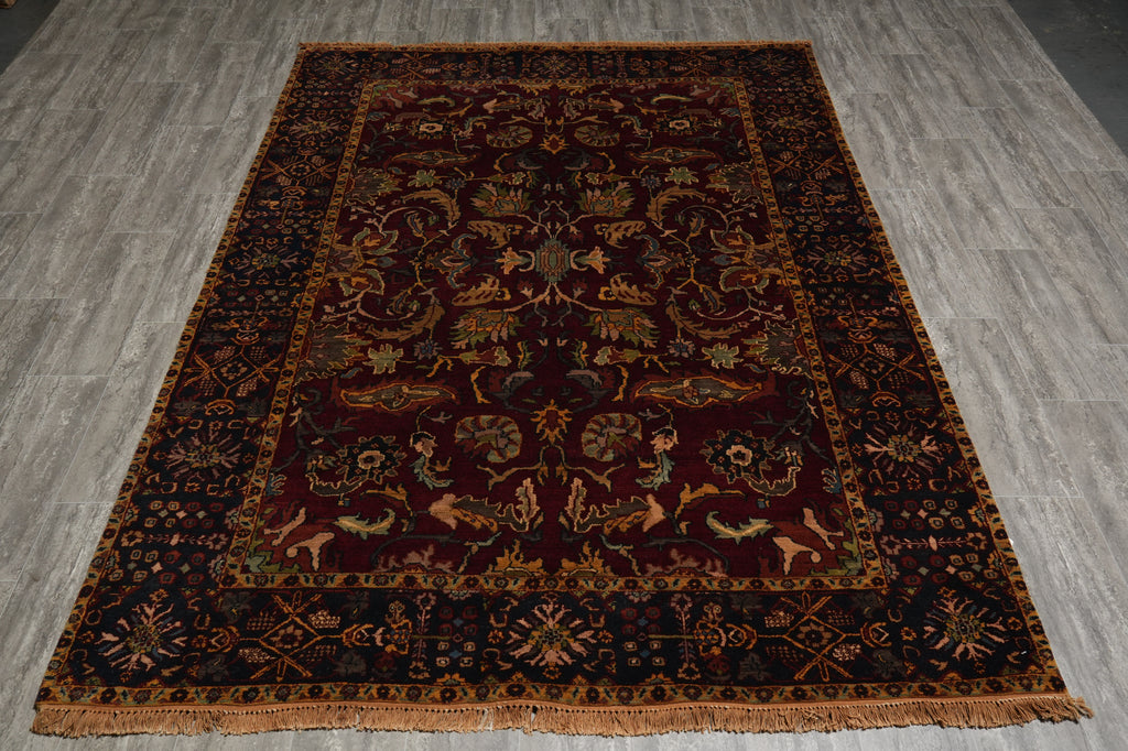 A rectangular traditional area rug with an intricate floral and animal pattern, laid flat on a gray wood-look floor. The rug features a dark red central field, a dark navy blue border, and accents of gold, beige, and green.