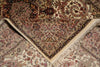 Load image into Gallery viewer, A close-up of a traditional oriental rug with an intricate floral and geometric pattern in beige, brown, and muted red tones, showing folded corners and cream fringe.
