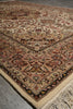 Load image into Gallery viewer, A traditional oriental area rug with an intricate floral and geometric pattern in beige, brown, red, and black, featuring a cream-colored fringed edge, shown laid out on a gray concrete floor.