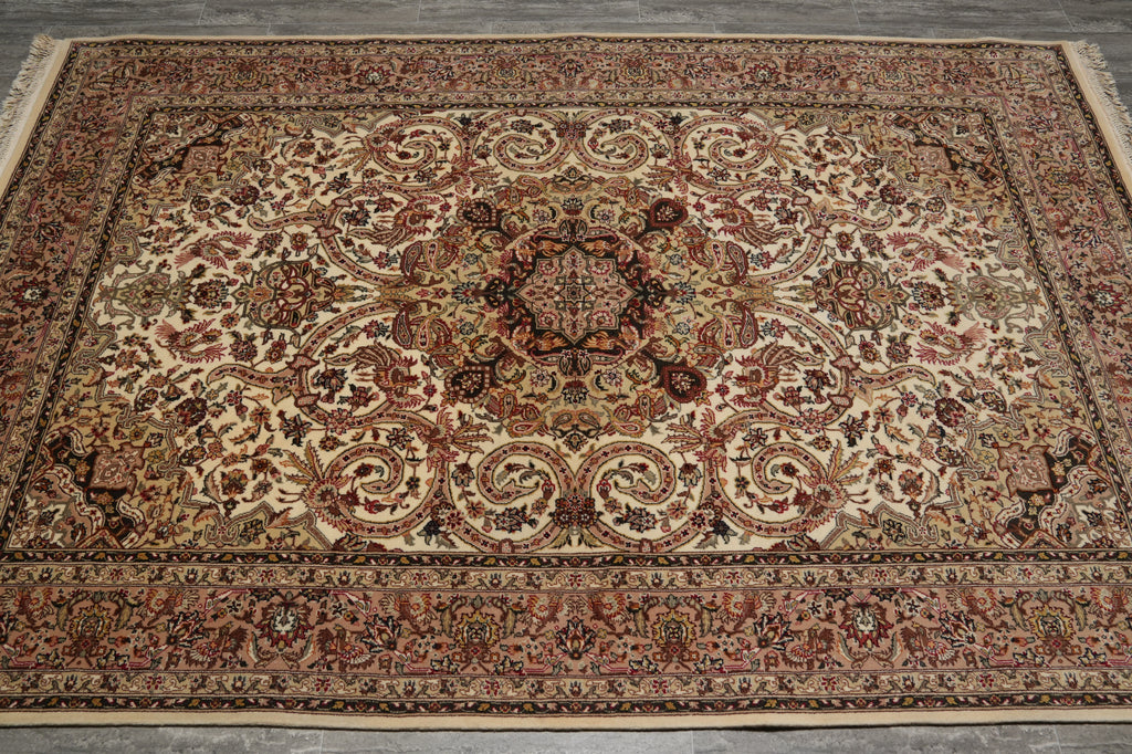 A traditional oriental area rug with an intricate floral and scroll pattern in shades of beige, rust red, brown, and black, laid out on a gray concrete floor.