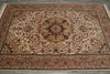 Load image into Gallery viewer, A traditional oriental area rug with an intricate floral and scroll pattern in shades of beige, rust red, brown, and black, laid out on a gray concrete floor.