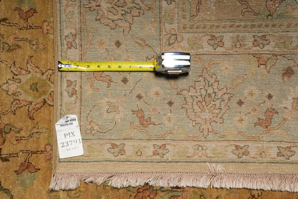 A square area rug with a traditional floral pattern in beige, brown, and muted orange tones, shown with a yellow tape measure across the middle and a white inventory tag reading PIX 23791.