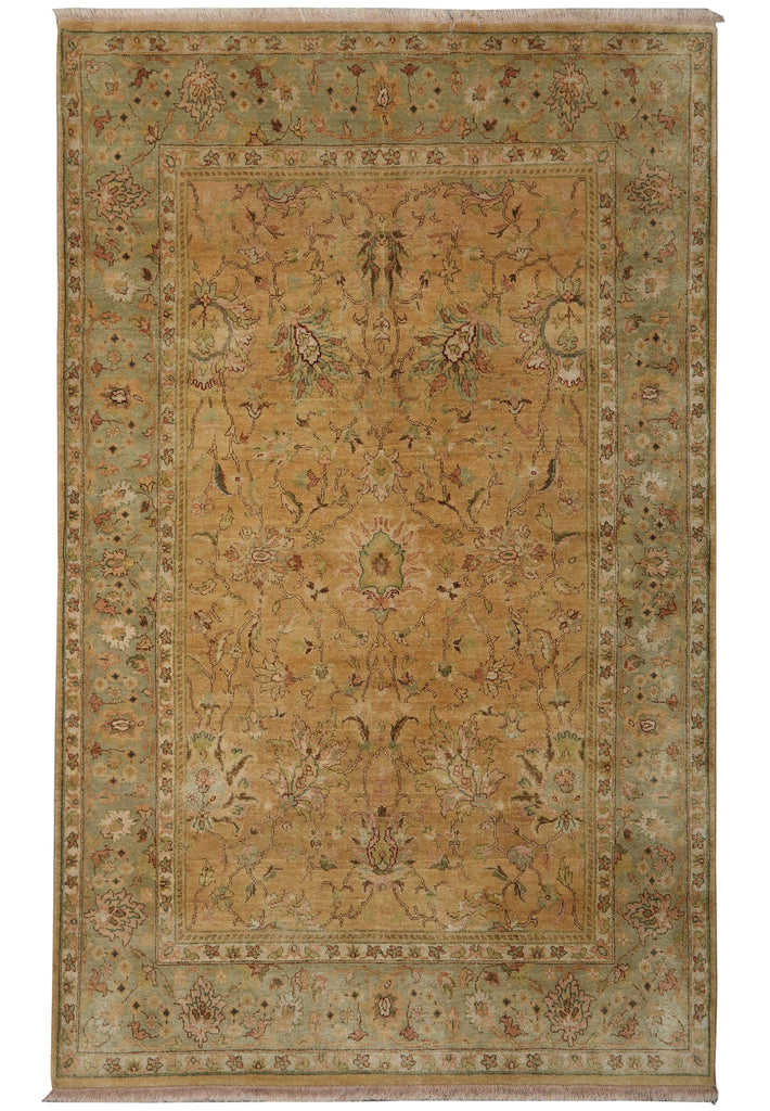 A rectangular traditional area rug with an ornate floral and botanical pattern, featuring a warm beige center, muted sage green borders, and cream fringe on the top and bottom.