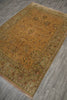Load image into Gallery viewer, A rectangular area rug with an intricate floral pattern, shown laid out on a gray wood-look floor. The rug features a dominant ochre-yellow center field, a muted sage-green border, and small red and blue accents in the detailed floral motifs.