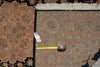 Load image into Gallery viewer, A close-up of a patterned area rug with a corner visible, showing a cream fringe edge, a black border, and a yellow tape measure placed along the inner corner for scale. A small white tag is attached near the tape measure.
