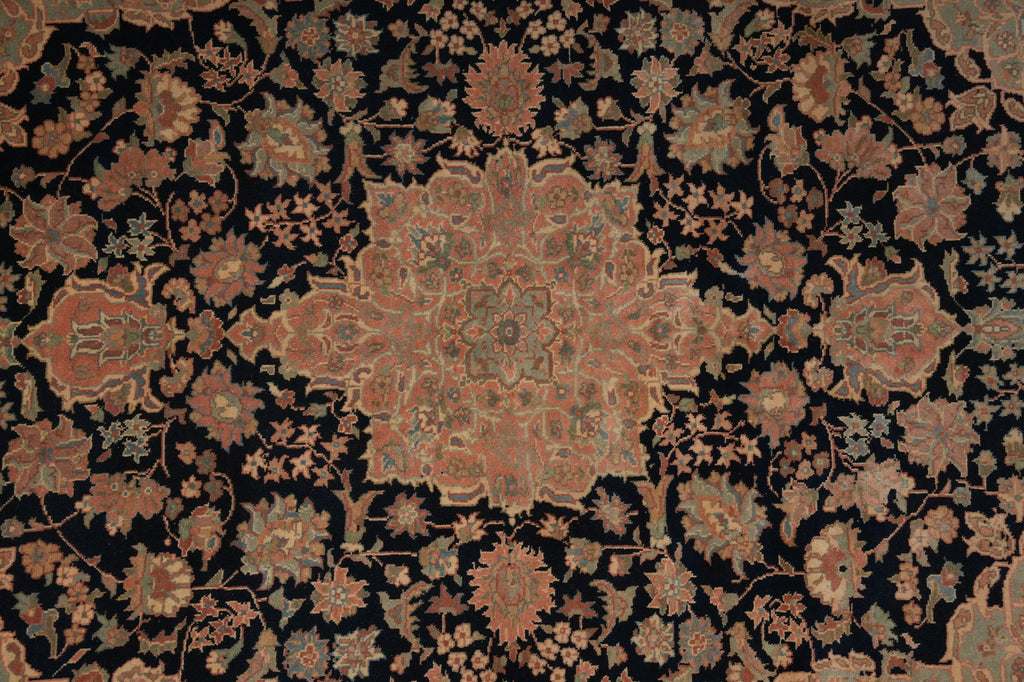 An ornate traditional patterned rug with a central medallion and surrounding floral motifs in muted rust, beige, and gray tones on a very dark black background.