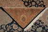 Load image into Gallery viewer, A close-up of an ornate patterned rug with a central medallion and corner fringe, shown layered over other rugs. The featured rug has a warm terracotta and beige base with navy, green, and cream floral details.
