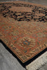 Load image into Gallery viewer, A traditional oriental-style area rug with a terracotta orange field, black border, and cream fringe, photographed on a gray concrete floor.