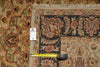 Load image into Gallery viewer, A close-up of a patterned area rug corner with a white size tag and a yellow tape measure laid across the border, showing the rug's detailed floral and geometric design in beige, navy, and rust tones.